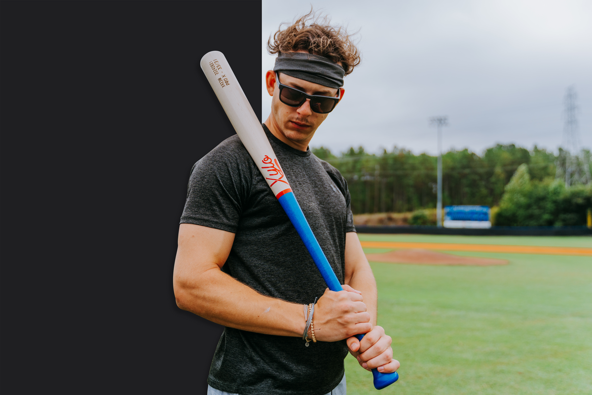 Baseball player holding a custom Xylo wood baseball bat on a baseball field.